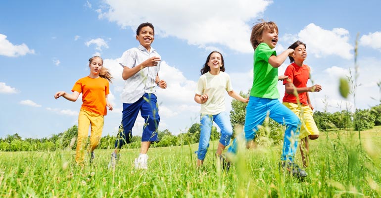 Barn som springer på ett grönskande fält.